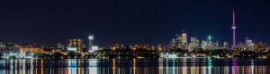 Picture of the Toronto Skyline at night with lights reflecting on the lake.