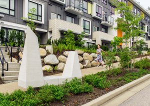 Girl running through UniverCity on Burnaby Mountain in front of a building