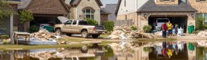 flooded street with people standing in front of house